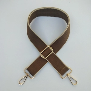Detail of adjustable canvas bag strap in brown and beige with gold metal hooks