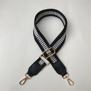 Detail of adjustable black woven strap with silver patterns and gold metal lobster clasps