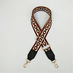 Detail of adjustable bag strap with brown and black geometric chain pattern and gold hardware
