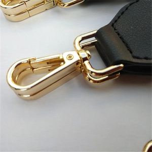 Macro detail of high-quality black leather bag strap with polished gold lobster clasp