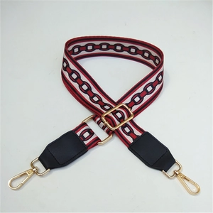 Adjustable woven shoulder strap with red and white geometric pattern and gold hooks