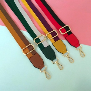 Detail view of adjustable canvas bag straps with colorful stripes and gold metal hooks