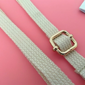 Détail de la bandoulière en toile de coton beige avec boucle réglable dorée