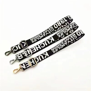 Close-up of adjustable woven purse straps with letter patterns and metal lobster clasps