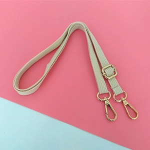 Bandoulière réglable en toile beige avec mousquetons dorés sur fond bicolore moderne