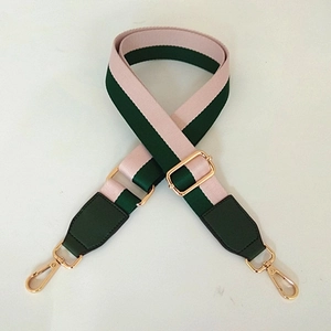 Macro detail of wide striped bag strap with gold metal swivels and adjustable buckle