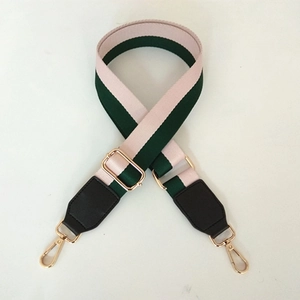 Detail of adjustable wide bag strap with pink and green stripes and gold metal hooks