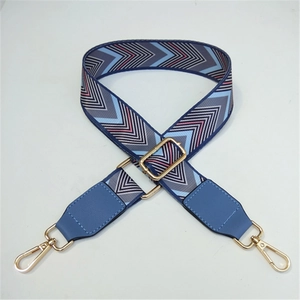 Detail of adjustable woven wide shoulder strap with blue geometric jacquard and gold hooks