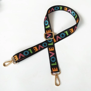Macro shot of adjustable black nylon strap with colorful LOVE embroidery and gold buckles