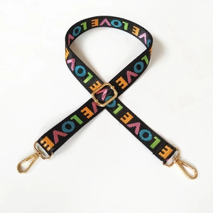 Close-up of adjustable black nylon strap with colorful LOVE embroidery and gold buckles