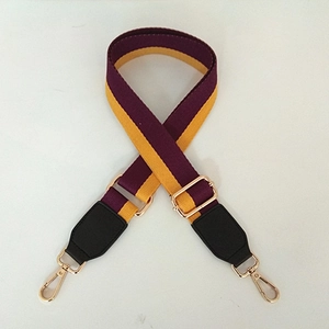 Detail of adjustable purple and yellow striped bag strap with gold metal hardware