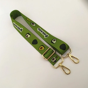 Detail of green nylon bag strap with avocado patterns and golden metal swivel lobster clasps