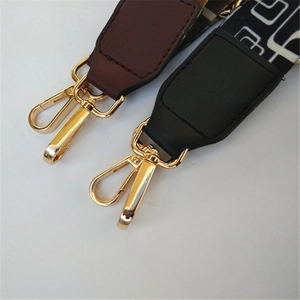 Detail of adjustable patterned bag strap with golden lobster clasp and leather joints