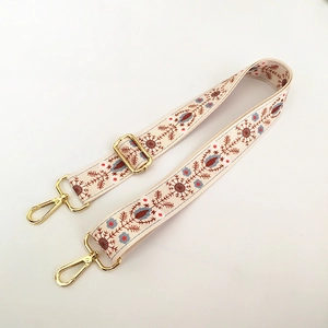 Close-up of floral embroidery on adjustable wide strap with gold metal lobster clasp