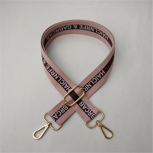 Detail of adjustable thick cotton strap with letter patterns and gold metal swivel hooks