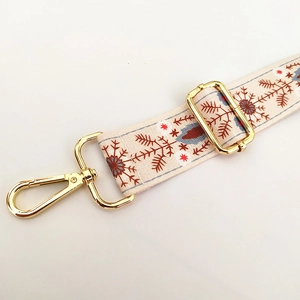 Macro detail of ethnic style bag strap with red floral pattern and gold metal hardware