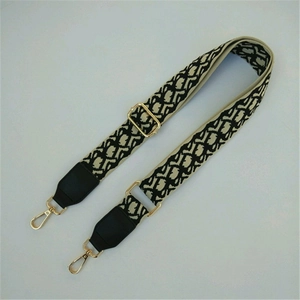 Detail of adjustable woven wide shoulder strap with jacquard pattern and gold metal buckles