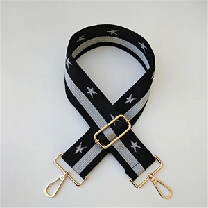 Detail of adjustable wide bag strap with star patterns and golden metal buckles