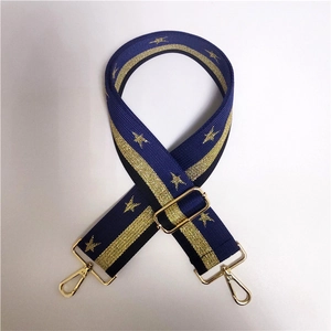 Close-up of blue wide fabric bag strap with gold stars and metal swivel hooks