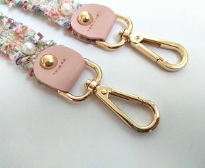 Close-up of multicolor tweed handbag strap with pink leather details and pearl accents