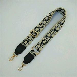 Detail of adjustable wide shoulder strap featuring woven dinosaur patterns and gold hooks
