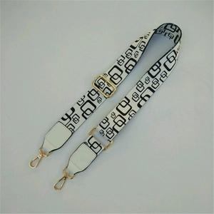 Detail of adjustable wide bag strap with black geometric pattern and gold metal hooks