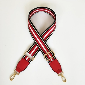 Close-up of wide striped woven shoulder strap with red leather ends and gold metal clasps