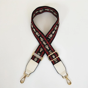 Close-up of geometric jacquard shoulder strap with gold metal hooks and white leather ends
