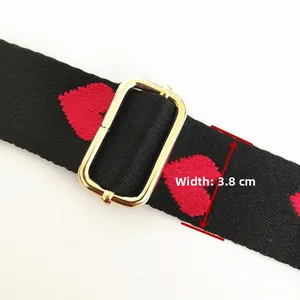 Detail of 3.8cm wide black woven bag strap with red heart embroidery and gold buckle