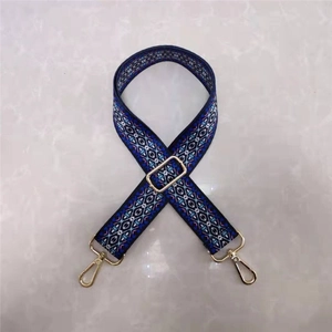 Detail of ethnic floral wide shoulder strap with blue geometric patterns and gold buckles
