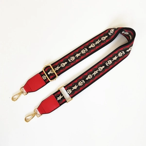 Close-up of ethnic geometric jacquard woven strap with red leather and gold hooks