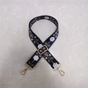 Close-up of floral embroidery on wide adjustable bag strap with gold metal hardware