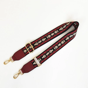 Close-up of ethnic geometric pattern wide strap with leather ends and golden metal hooks