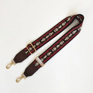 Close-up of ethnic geometric pattern webbing strap with golden lobster clasps