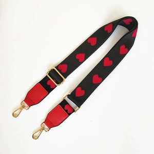 Detail of ethnic style adjustable bag strap with red heart pattern and gold hardware