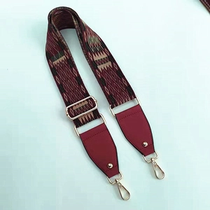 Detail of adjustable ethnic geometric bag strap with wine red leather and gold metal hooks