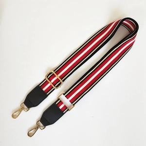 Detailed view of woven red and black striped shoulder strap with gold metal buckles