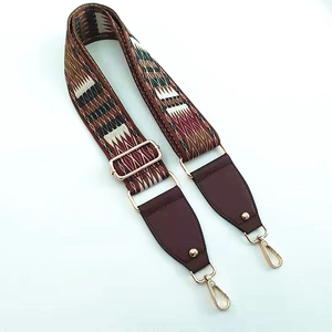 Close-up of ethnic geometric pattern wide bag strap with gold metal buckle and leather ends