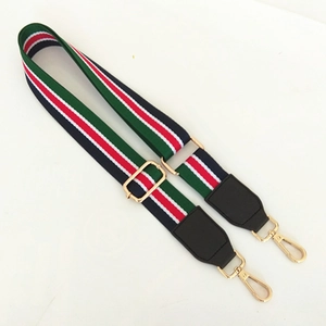 Close-up of adjustable striped shoulder strap with gold metal buckles and leather ends