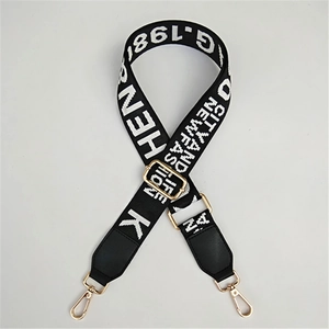 Detail of adjustable black woven shoulder strap with white letters and gold metal clips
