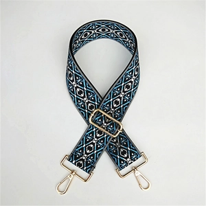 Detail of adjustable geometric folk pattern wide bag strap with gold metal hooks