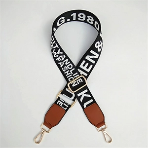 Detail of adjustable woven bag strap with letter patterns and brown leather ends