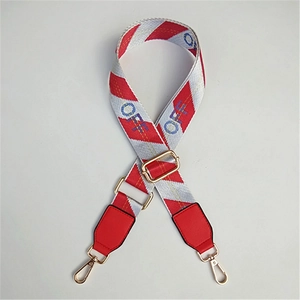 Detail of adjustable red and white striped bag strap with gold metal hooks and red faux leather