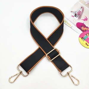 Detail of adjustable black nylon bag strap with brown stitching and gold metal hooks