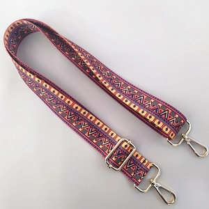 Macro detail of Bohemian geometric patterned bag strap with golden metal lobster clasps