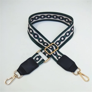 Close-up of wide fabric shoulder strap with geometric chain patterns and gold metal hooks