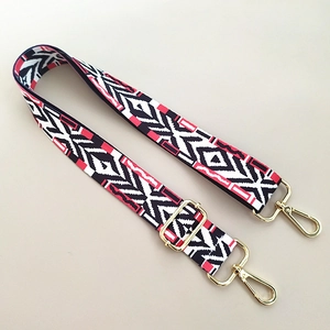 Close-up of ethnic geometric pattern wide strap with gold metal hooks for handbags