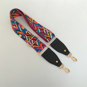 Detail of adjustable woven guitar-style bag strap with ethnic geometric patterns and gold hooks