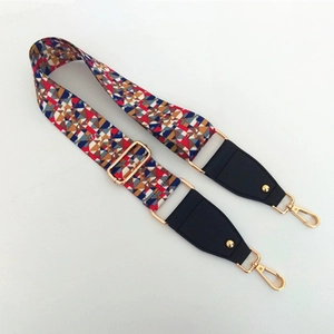 Close-up of ethnic style woven bag strap with colorful geometric patterns and gold clips
