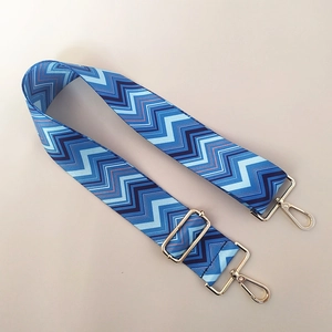 Close-up of blue zigzag pattern wide bag strap with golden metal swivel hooks